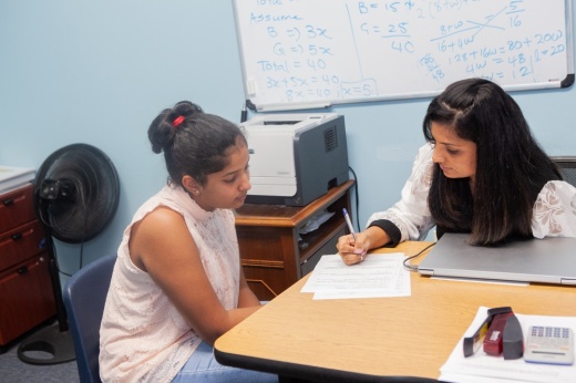 A teacher helps a student at a desk