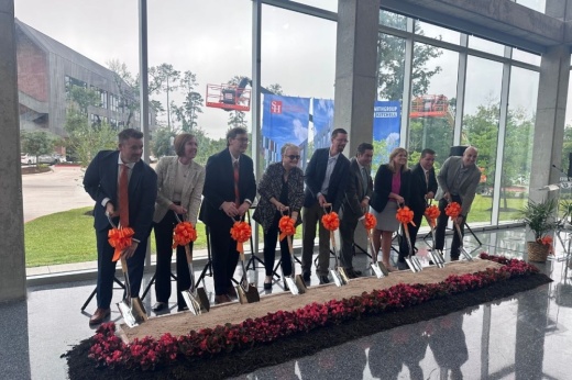 people indoors push shovels into a row of dirt