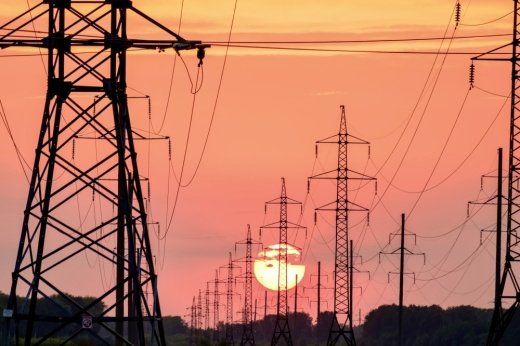 Power lines in front of a red and orange sunset.