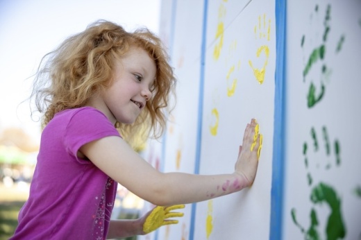 Picture of a girl creating an art wor with a painted hand.