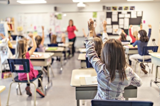 students in a classroom raising their hands