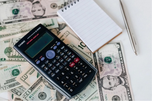 calculator and note pad on top of money