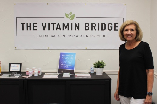 Female standing near a banner with The Vitamin Bridge wording.