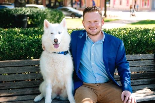 Male sitting with white dog on a bench.