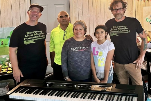 A child and adults standing by a keyboard.
