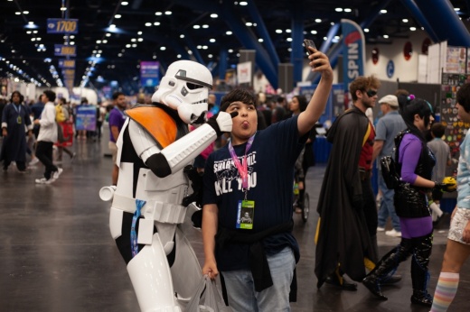 a child takes a selfie photo with a person in a stormtrooper costume