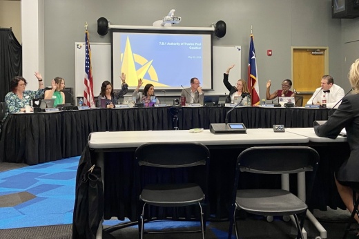 The board of trustees raise their hands to take a vote