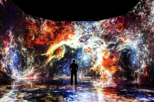 a person stands in front of colorful space imagery on a large wall