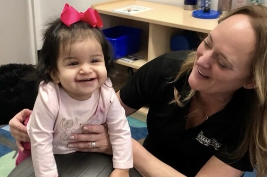 a preschool teacher smiles with a child