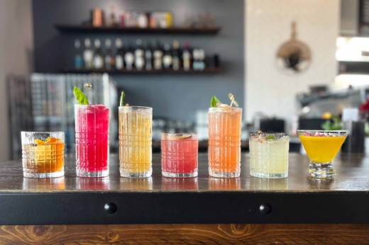 Several cocktails sit on a table in front of a bar