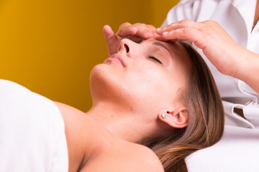 a woman lays on a table while receiving a facial skin treatment