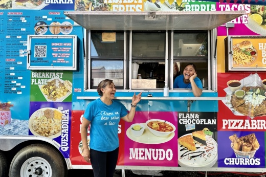 The two women smile and laugh in front of the truck.