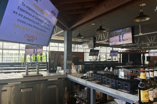The indoor space is shown with televisions, a bar, and long tables for seating.