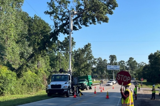 Crews work July 9 to remove a tree leaning against a power line along Hardin Store Road near Magnolia. (Kelly Schafler/Community Impact)