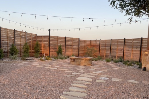 A backyard with string lights and a fire pit incorporate xeriscaping into the landscape.