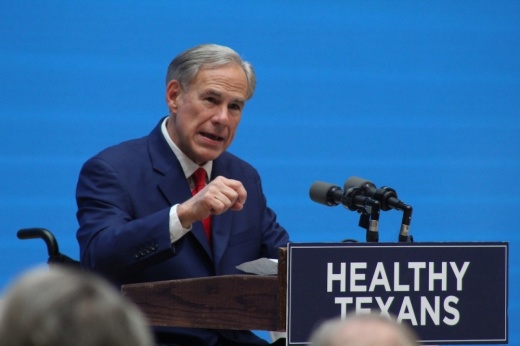 a man in a wheelchair speaks into a microphone in front of a crowd