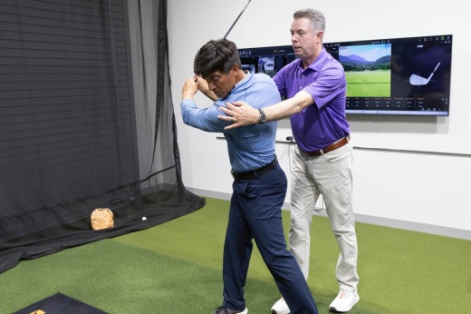 Head Coach Tim Cusick helps a golfer improve his swing at the PGA Coaching Center.