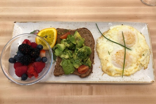 Avocado toast, over medium eggs, bowl of fruit