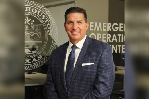 a portrait photo of a man in a suit standing in front of a glass door for houston's office of emergency management
