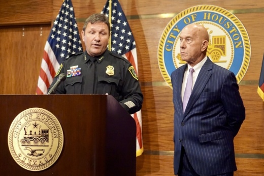 two men stand at a podium, one wearing a police uniform and one wearing a suit
