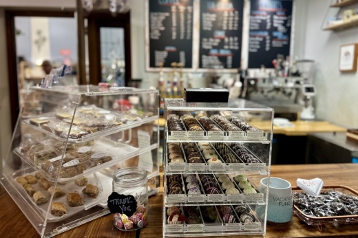 Displays filled with desserts are shown in the foreground, with coffee in the background.