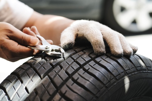 A technician pulling a nail out of a tire.