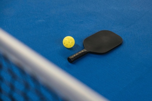 pickleball racket and ball on blue court with net