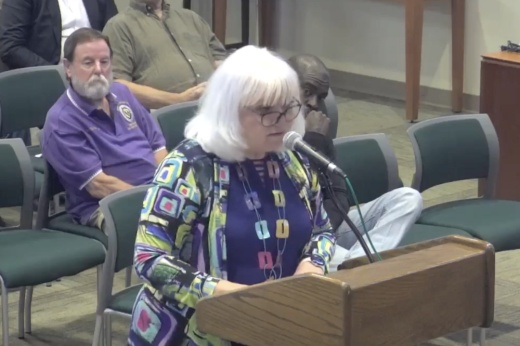 The city secretary stands before the dais during a meeting.