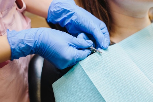 A nurse clips a medical bib around a dental patient's neck.