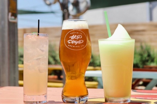 An image of three drinks with the one in the middle displaying Hopsquad Brewing Co. branding on the glass.