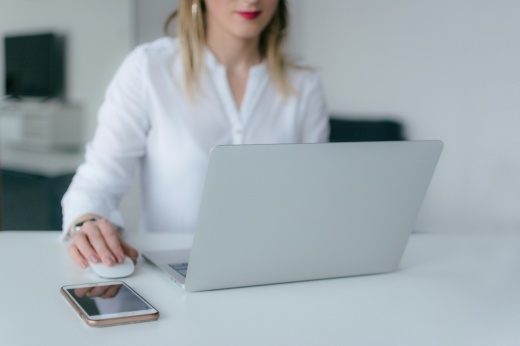 A woman sits at a desk working on her laptop.