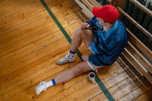 Man sitting on wood floor in coach outfit