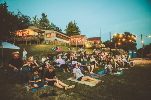 People sit around the stage at Neighbor's Kitchen and Yard at dusk.