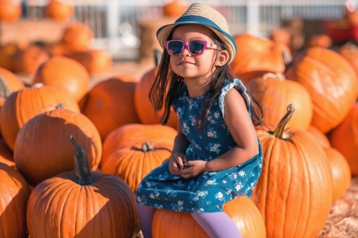 A child sits on a pumpkin.