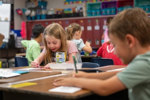 Two elementary students color at their desks