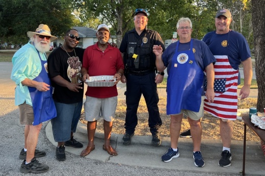 A group of people pose outside for a pic—some wearing aprons.