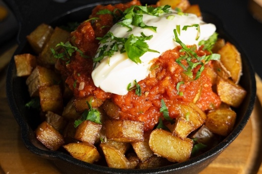 Tapas dish in a skillet topped with sour cream and chives