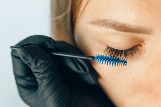 Eyelashes being combed by a gloved hand