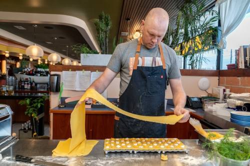 a man holds a long segment of dough over a table