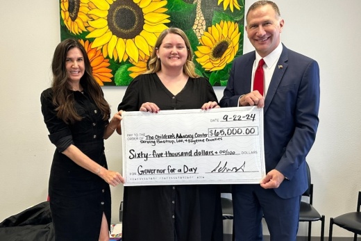 The three people hold a check and smile.