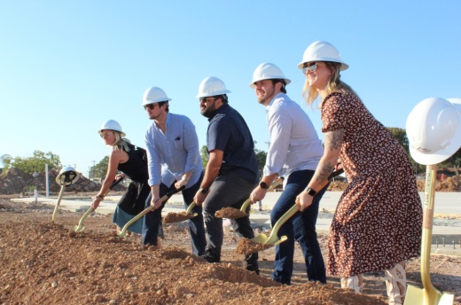 Employees pose shoveling dirt.