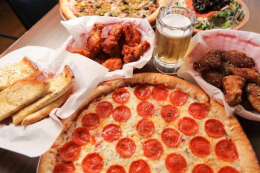 Pepperoni pizza with table of food and drinks