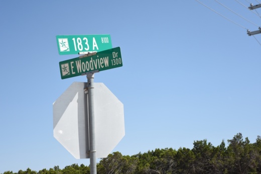 Street signs show the names of the roads 183 A Toll and E. Woodview at the intersection of the two roads.