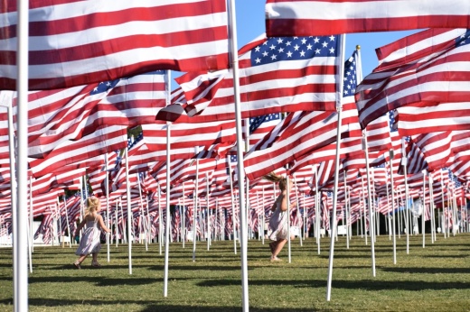 An image of two kids running in between the flags at a previous Field of Honor.