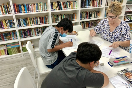 A tutor teaches two students at a test