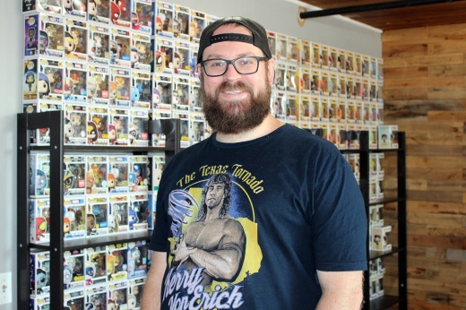 Male standing in front of a wall filled with Funko Pop figures.