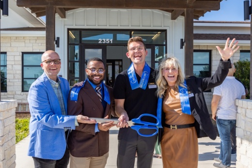 Four adults hold scissors after a school's ribbon-cutting.