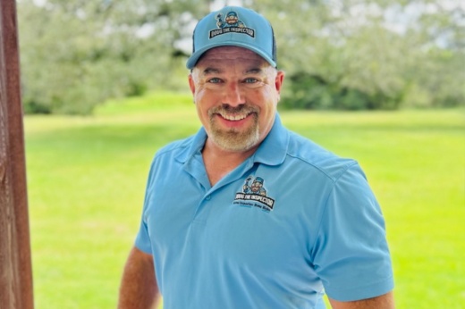 Doug Berryann smiles while wearing a blue shirt and hat with his company logo.