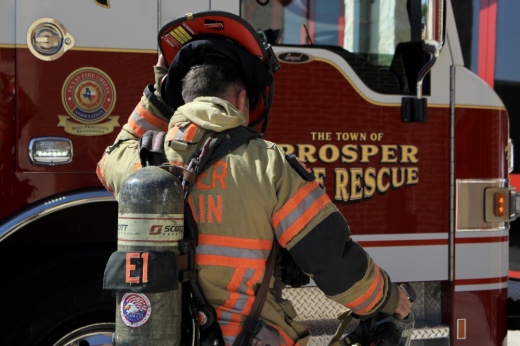 Zach Stringer, a captain and paramedic with Prosper Fire Department, puts on his helmet beside a fire engine. Prosper's fourth fire station is expected to open in 2026. (Alex Reece/Community Impact)