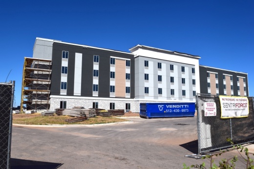 The outside of the building is shown, dominated by black, white and grey colors, and a blue sky is overhead.